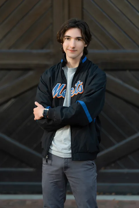 Cade in a jacket in front of a wooden door